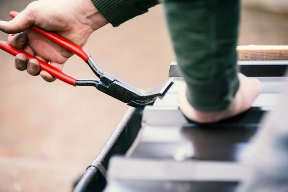 Hand biegt Blech mit Zange